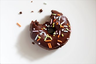 Overhead view of partially eaten donut with chocolate icing and sprinkles