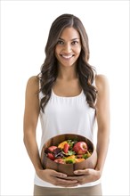 Studio portrait of smiling woman holding bowl of fruit