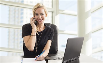 Portrait of smiling businesswoman talking on phone in office