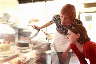Owner with daughter (10-11) looking at bakery display