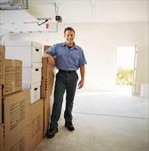 Portrait of man leaning on boxes in garage