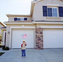 Boy (6-7) waving US flag in front of house