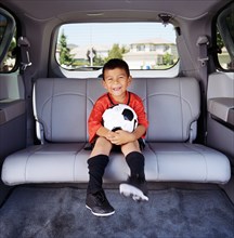 Portrait of boy (4-5) in soccer uniform sitting in car