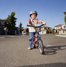 Boy (6-7) with helmet riding bicycle