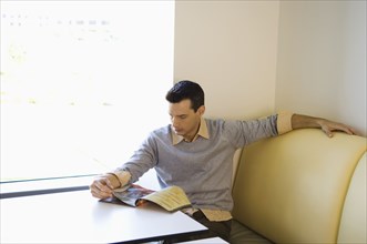 Businessman reading magazine in cafeteria