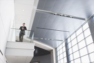 Businessman leaning on balcony in building lobby