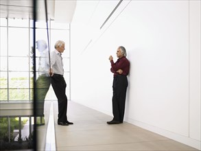 Two businessmen meeting in modern office hallway