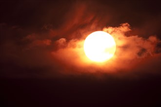 Dramatic sun with orange clouds in sunset sky