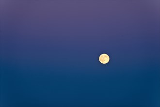 Full moon against blue sky