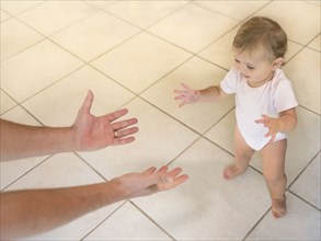 Father reaching hands to baby girl