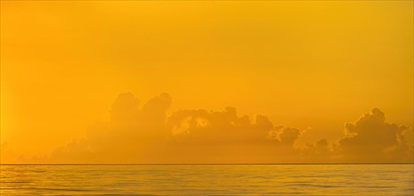 Golden sunrise clouds over calm ocean