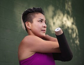 Athletic woman with amputated hand stretching arm