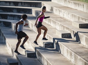 Athletic man and woman with amputated hand running up steps