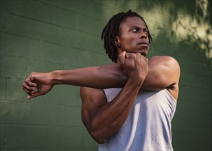 Athletic man stretching arm outdoors