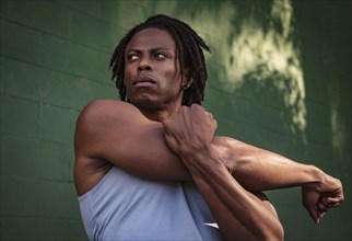 Athletic man stretching arm outdoors