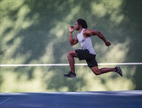 Athletic man running in front of wall
