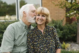 Senior man kissing woman in backyard