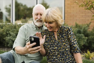 Smiling senior couple having video call in back yard