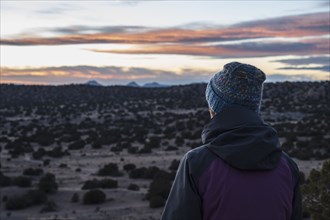 Rear view of woman in desert landscape at sunset