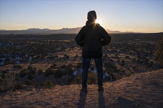 Rear view of man in desert landscape at sunset