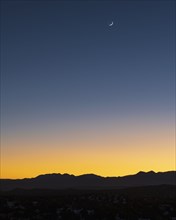 Jemez Mountains at dusk with crescent moon on sky