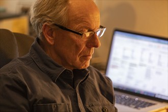 Portrait of senior man with laptop in background