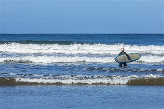 Senior surfer carrying surfboard
