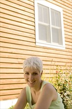 Mature woman standing in front of house