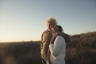 Older Caucasian couple hugging outdoors