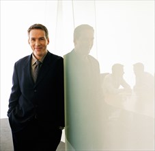 Portrait of business executive leaning against glass wall
