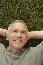 Mature man lying on grass and smiling