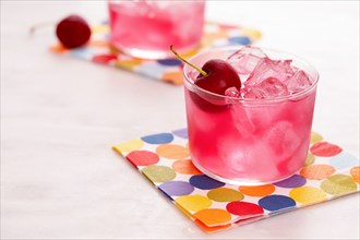 Red mocktail with cherry on colorful napkin