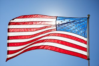 American flag in sunlight against clear blue sky