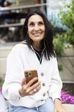 Smiling woman using phone and headphones