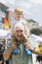 Portrait of grandfather carrying grandson