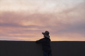 Rear view of man looking at wildfire smoke at sunset