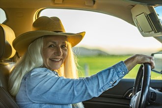 Senior woman in car wearing cowboy hat
