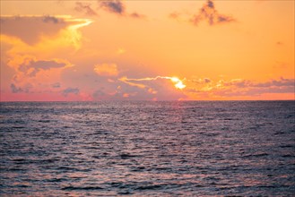 Dramatic orange sky above ocean at sunrise