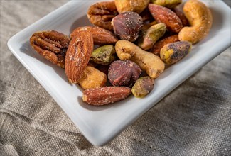 Close-up of small dish of assorted nuts on linen table cloth