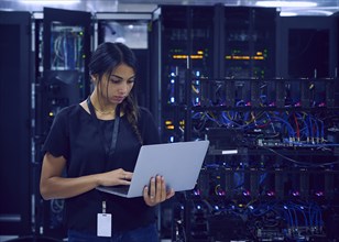 Female technician using laptop in server room