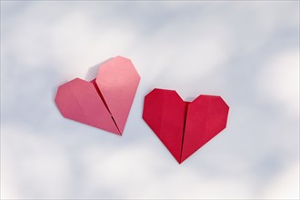 Red and pink origami hearts on white background