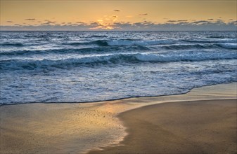 Ocean waves washing beach at sunset