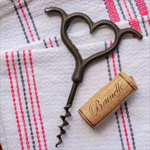 Vintage heart shaped corkscrew and wine cork on dish towels
