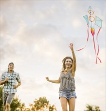 Smiling couple flying kite in park