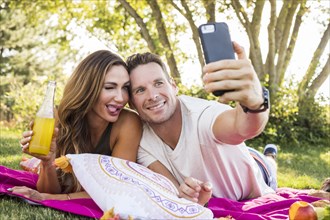 Smiling couple taking selfie in park