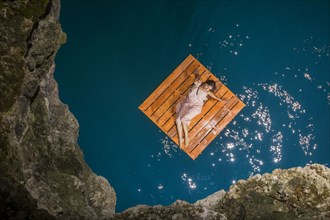 Aerial view of woman lying on wooden raft