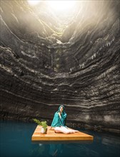 Woman sitting on wooden raft in cenote