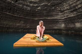 Woman sitting on wooden raft in cenote