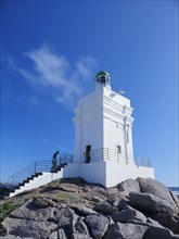 Woman climbing white lighthouse on sea coast