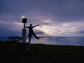 Woman standing on sign post on sea coast